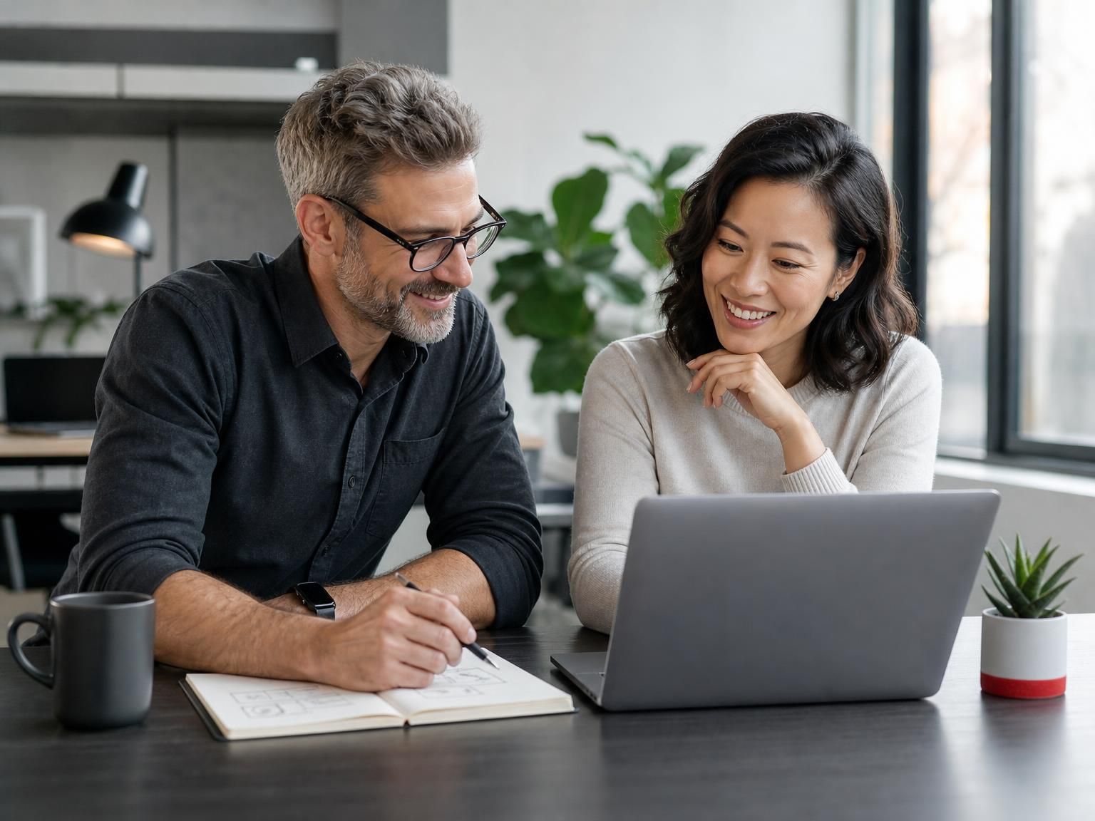 A consultant and a client working through a plan together at a laptop.