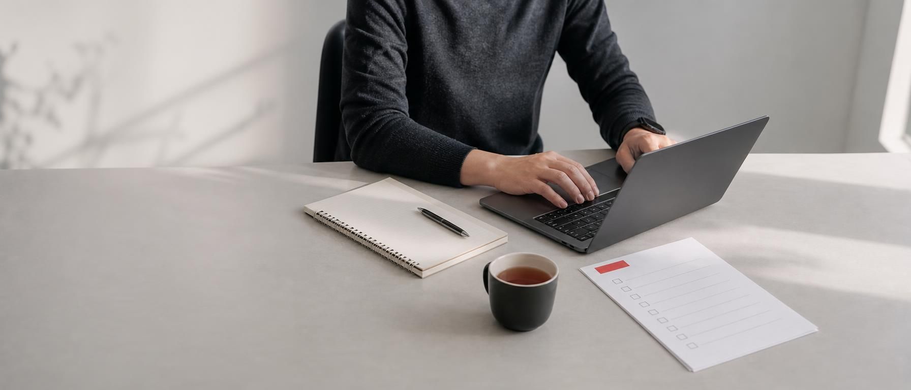 A person studying at a desk with a laptop and notebook.
